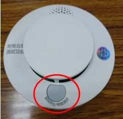臺北市消防局示範照片：紅圈標出這款住警器的測試按鈕；其他型號位置以手冊為準。